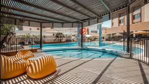 A pool area with a modern design, including a unique seating area and a view of the surrounding buildings. - Jacob Eilat (Eilat)