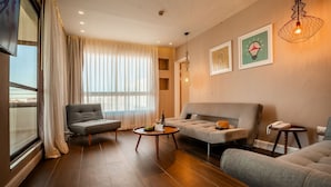 A modern living room with a grey sofa, a grey armchair, a wooden coffee table, and a small side table with a telephone. - Jacob Eilat (Eilat)