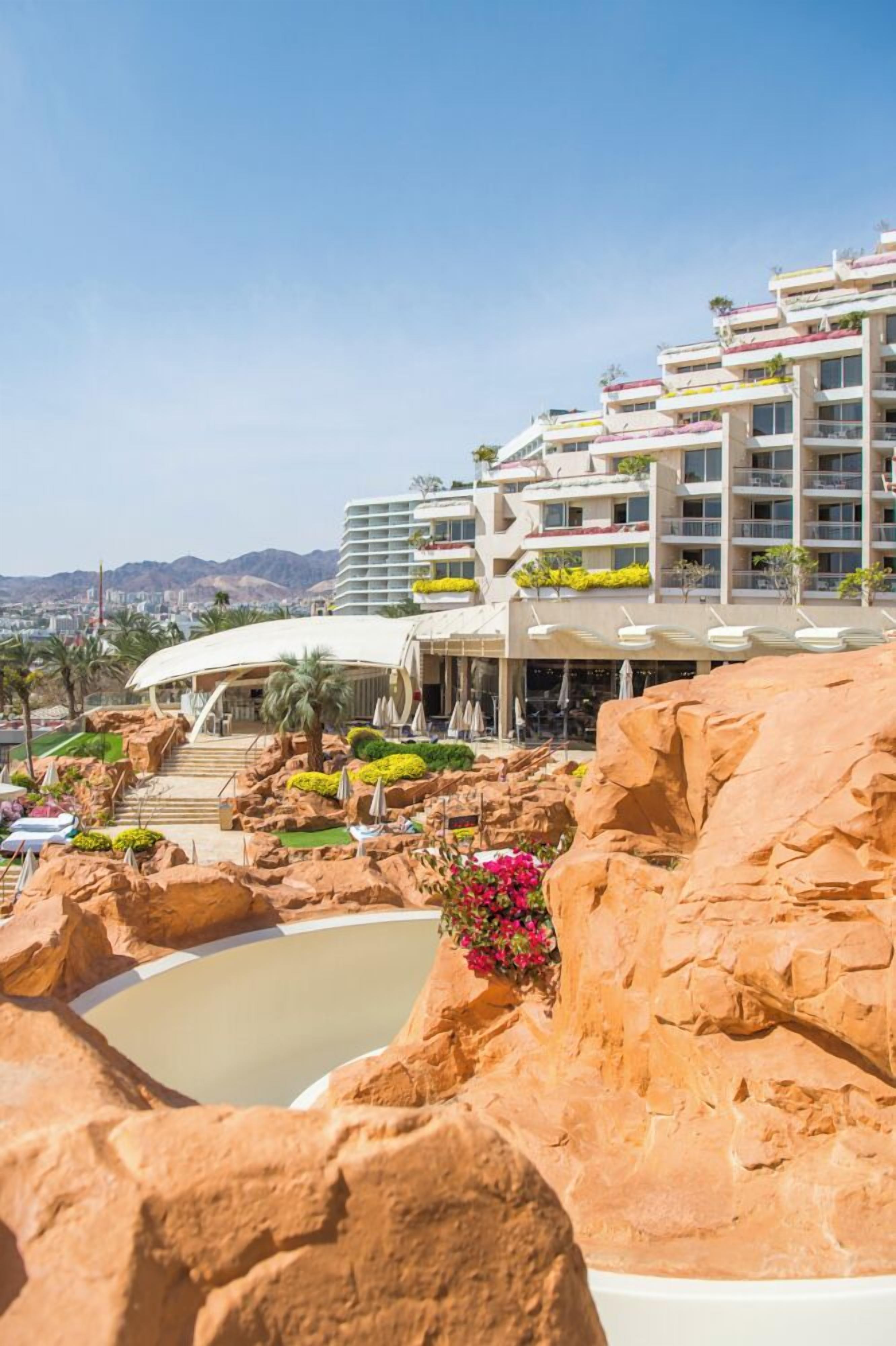 Un hotel con varios balcones, piscina y vistas a la ciudad.