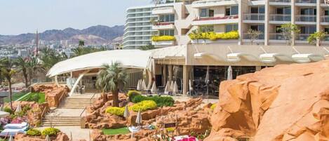 Un hotel con varios balcones, piscina y vistas a la ciudad.
