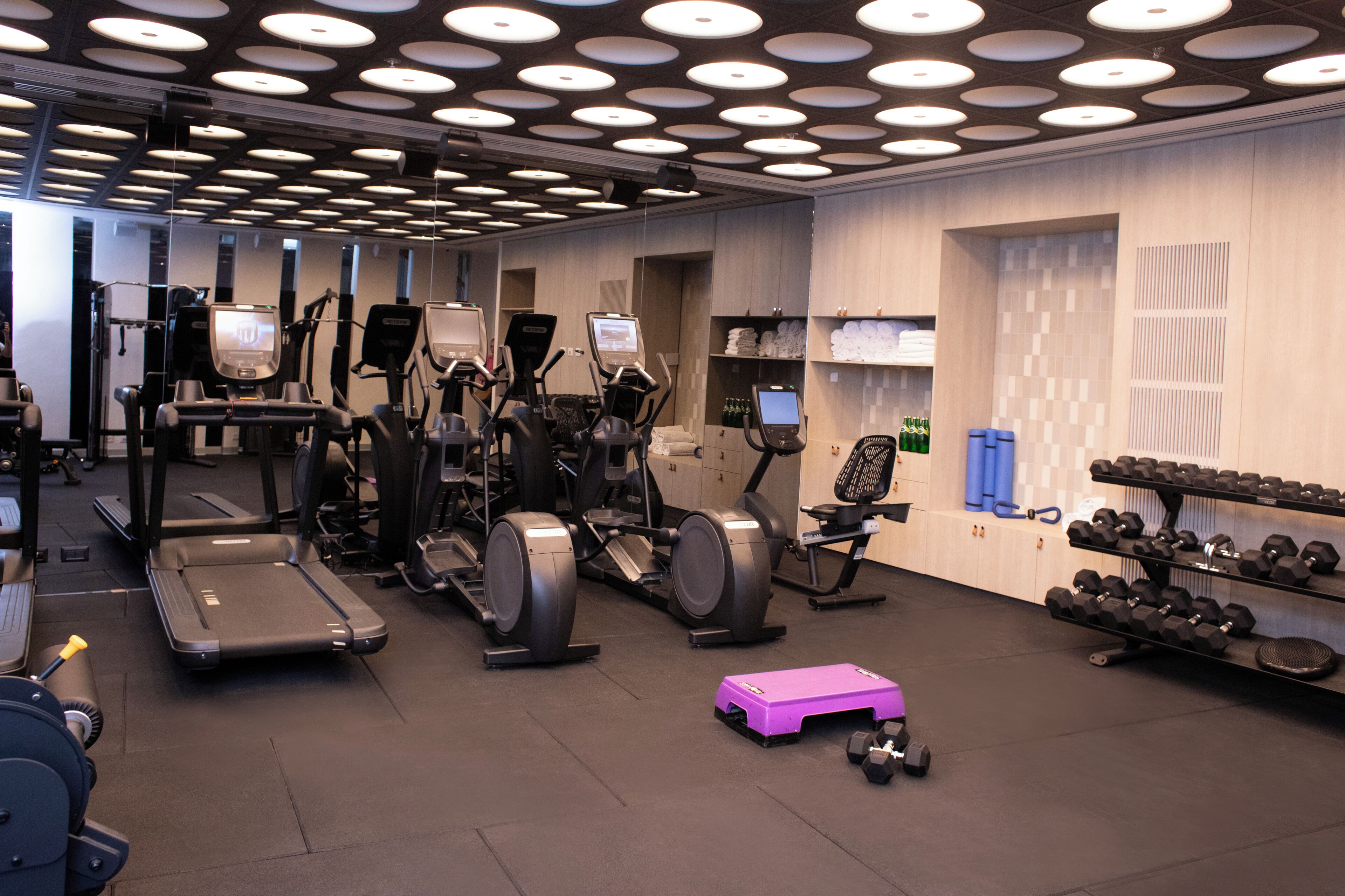 A gym with treadmills, elliptical machines, and a purple step platform.