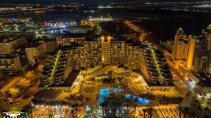 Een hotel met een centrale binnenplaats, meerdere zwembaden en een groot gebouw met een opvallend dak.