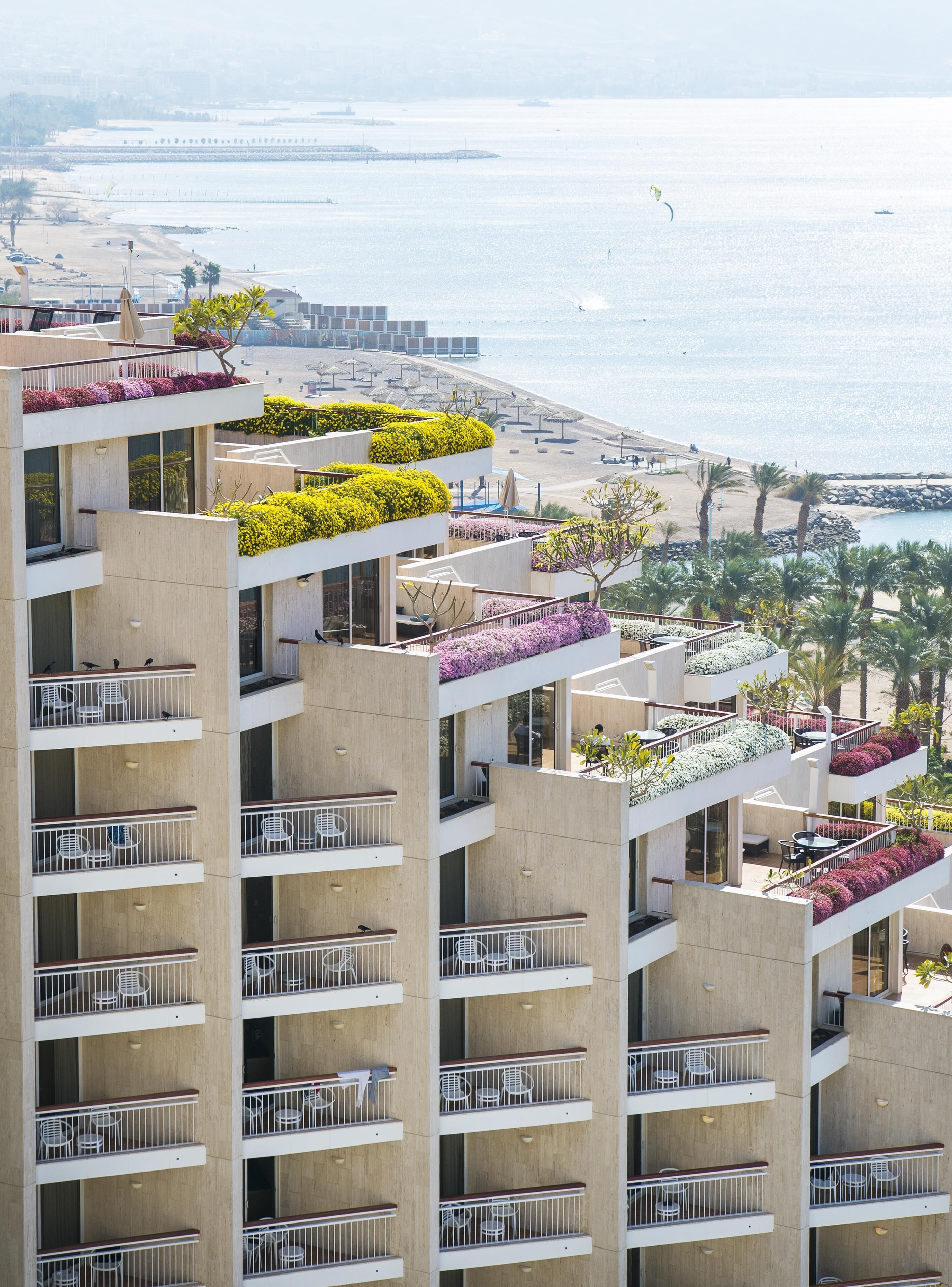 A multi-story hotel with balconies, some with plants.