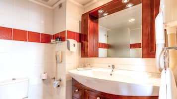 A bathroom with a white sink, wooden vanity, and a large mirror.