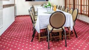 Ein Konferenzraum mit weißem Tisch, Stühlen und einer großen Leinwand an der Wand.