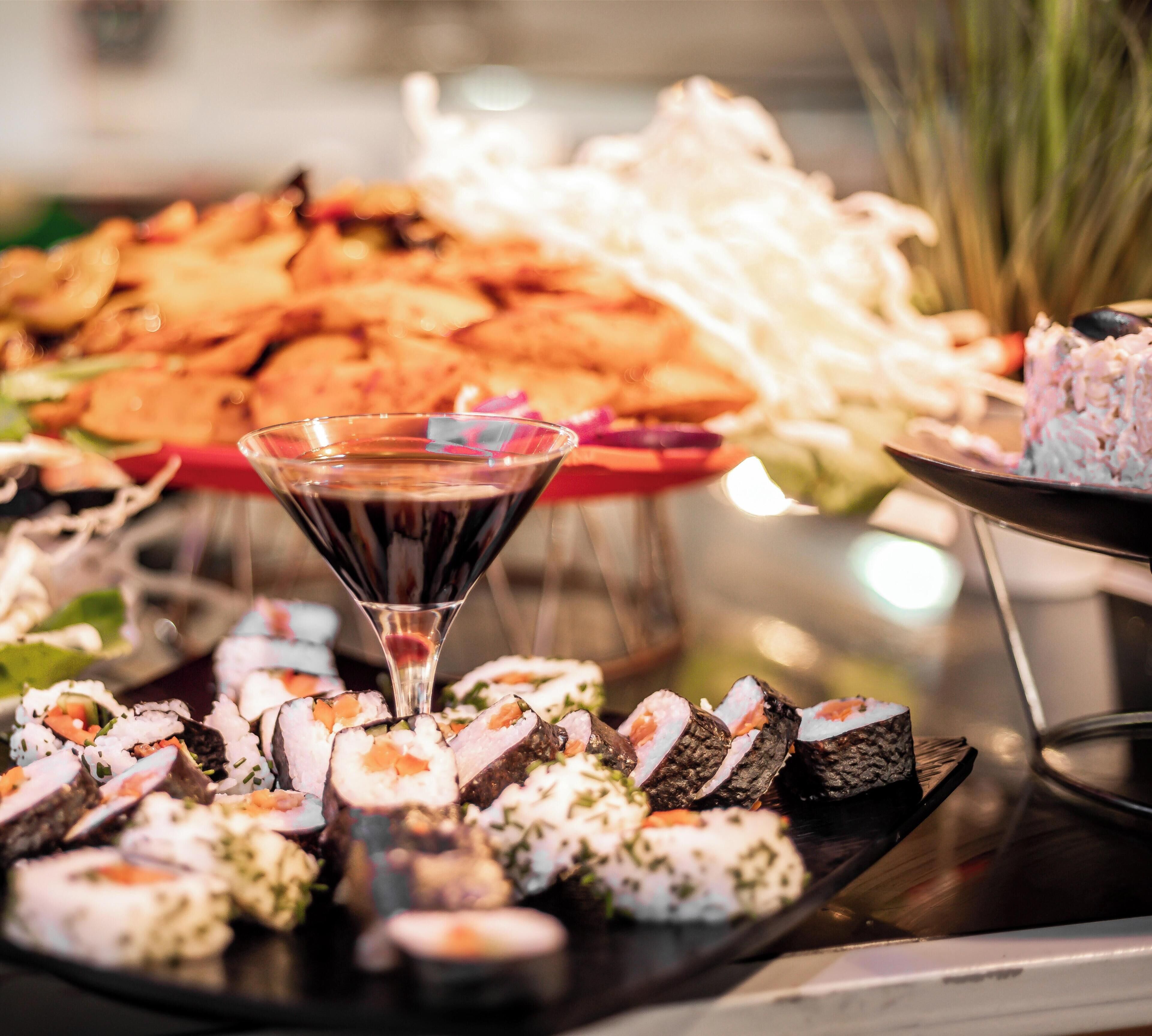 Una variedad de sushi y otros platos en una bandeja, con una copa de martini en el centro.