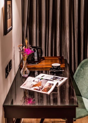 A wooden table with a vase of flowers, a coffee maker, a cup, and a magazine. - Jerusalem Gate Hotel (Jerusalem)