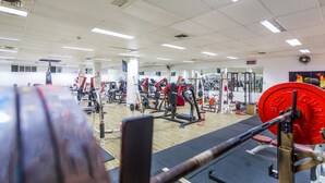 Une salle de sport équipée de divers appareils d’exercice, notamment des machines de musculation et des poids libres.