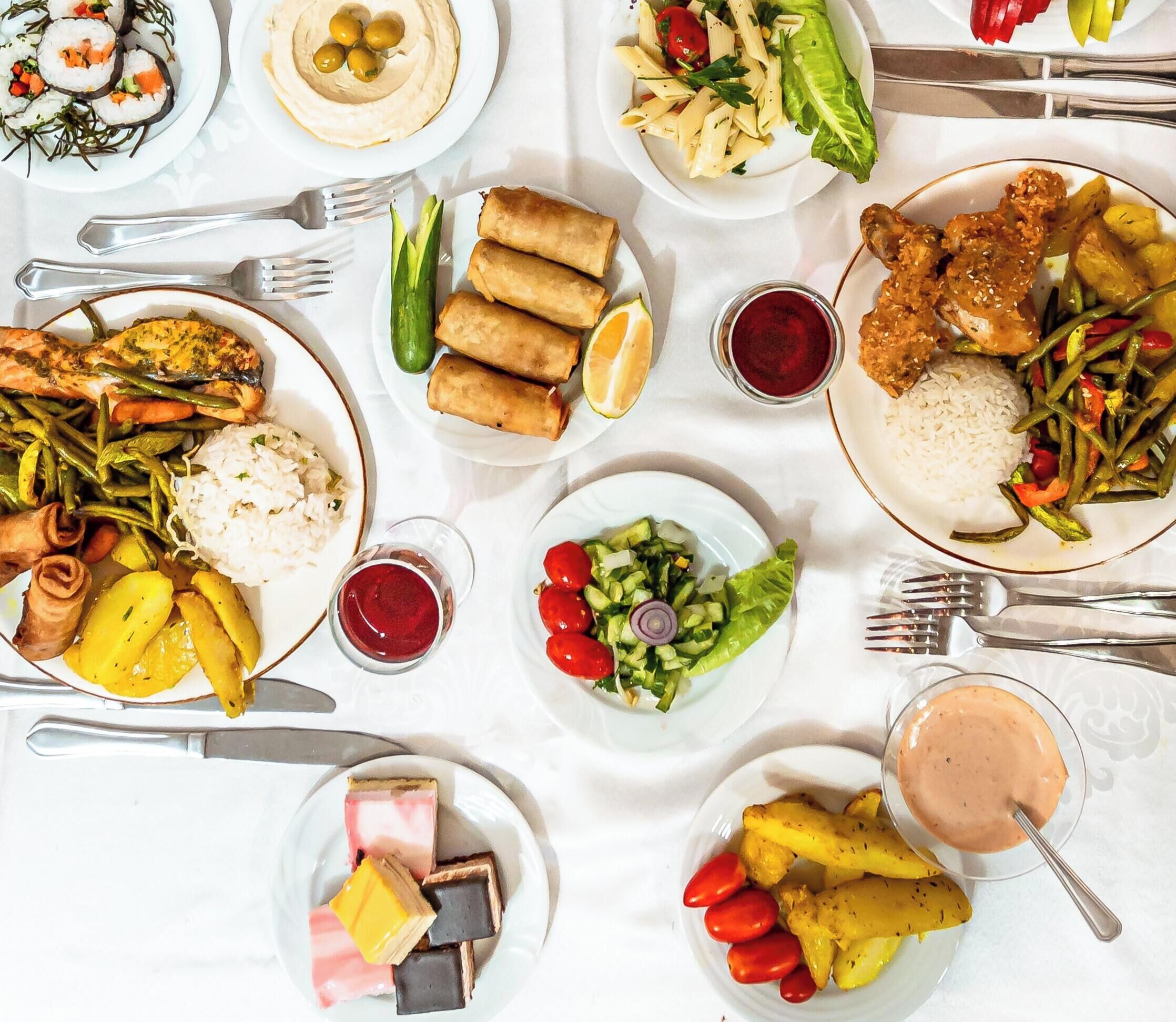 A variety of dishes including sushi, spring rolls, and a salad, suggesting a diverse meal selection.