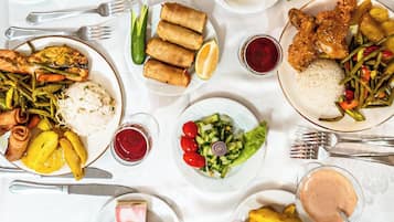 Variedad de platos que incluyen sushi, rollos primavera y una ensalada, lo que sugiere una amplia selección de comidas.