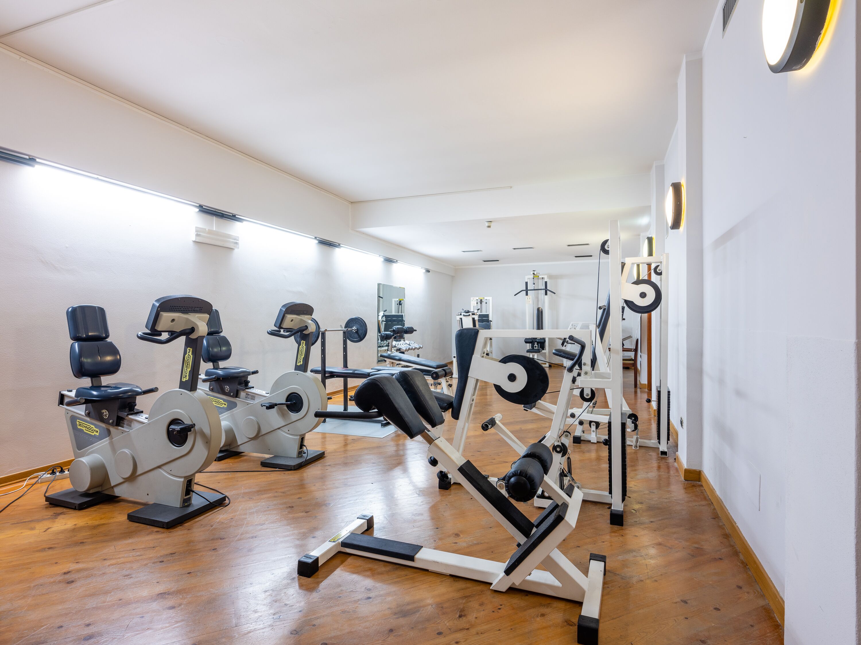 Une salle de sport équipée de divers appareils d’entraînement, notamment des tapis de course, des appareils de musculation et des poids libres.