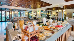 Zona de bufé con diversas opciones de comida y una sala de estar con mesas y sillas.