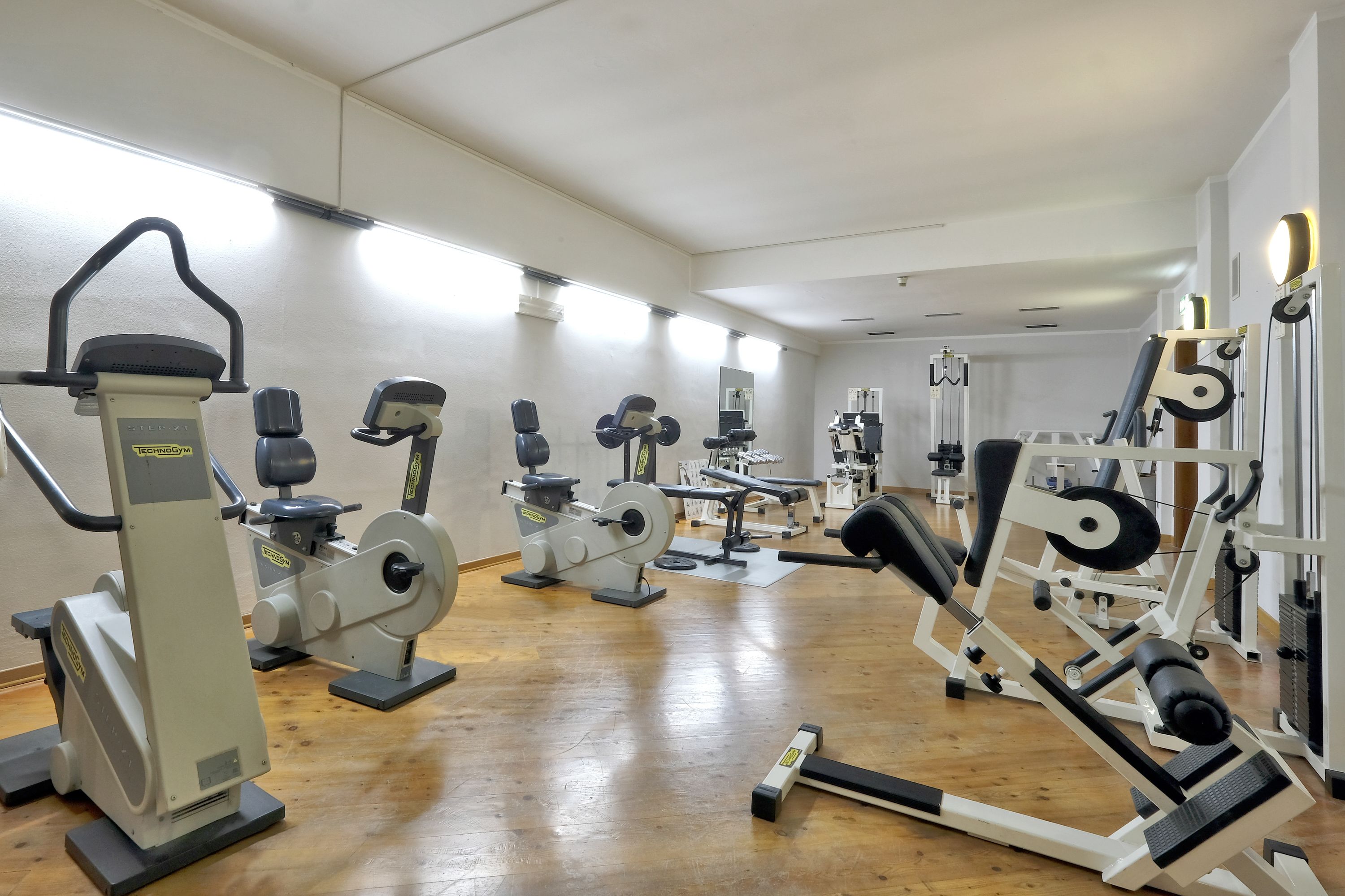 A gym with various exercise machines, including treadmills, weight machines, and free weights.