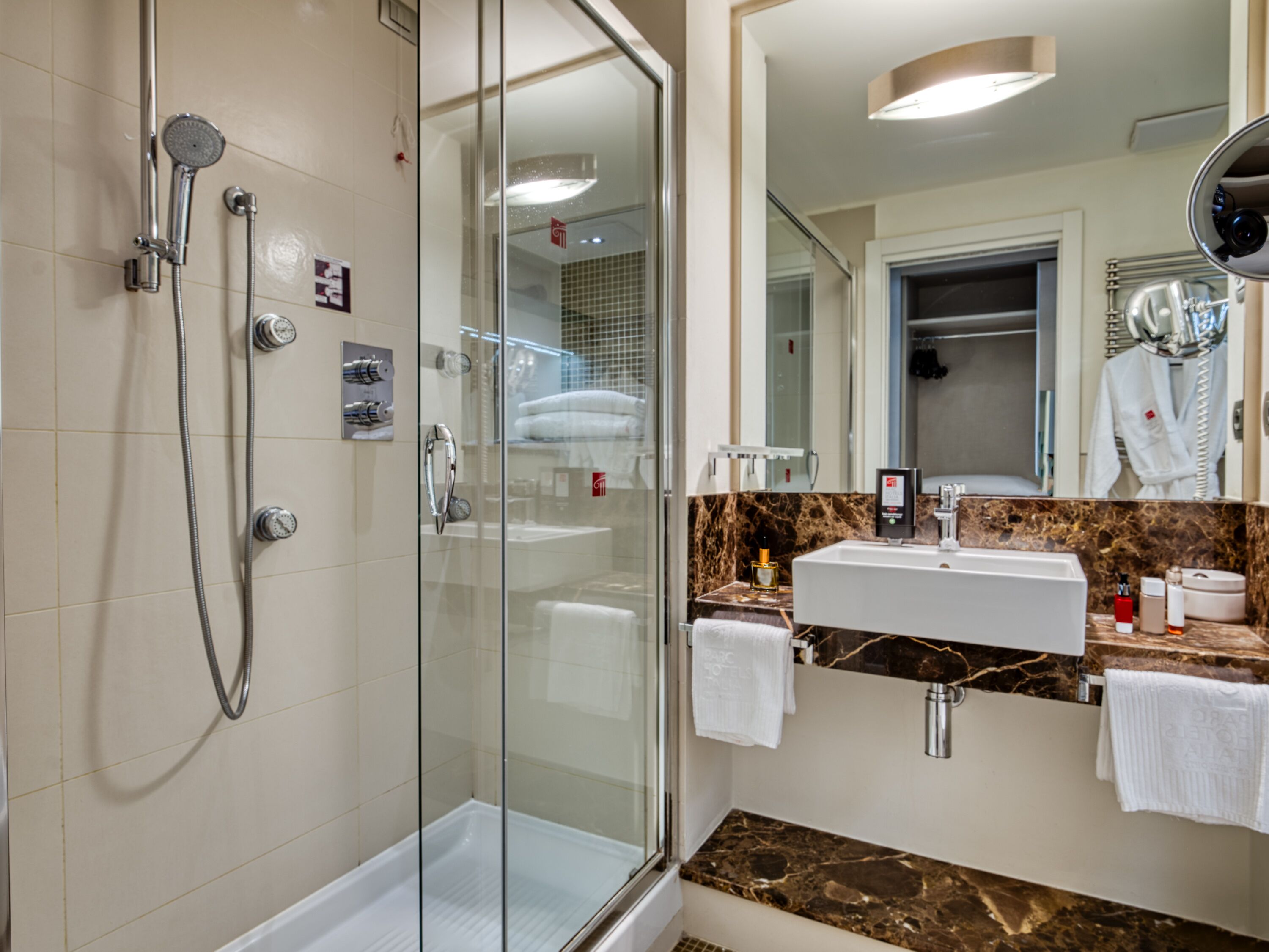 A modern bathroom with a glass-enclosed shower, a vanity with a marble countertop, and a large mirror.
