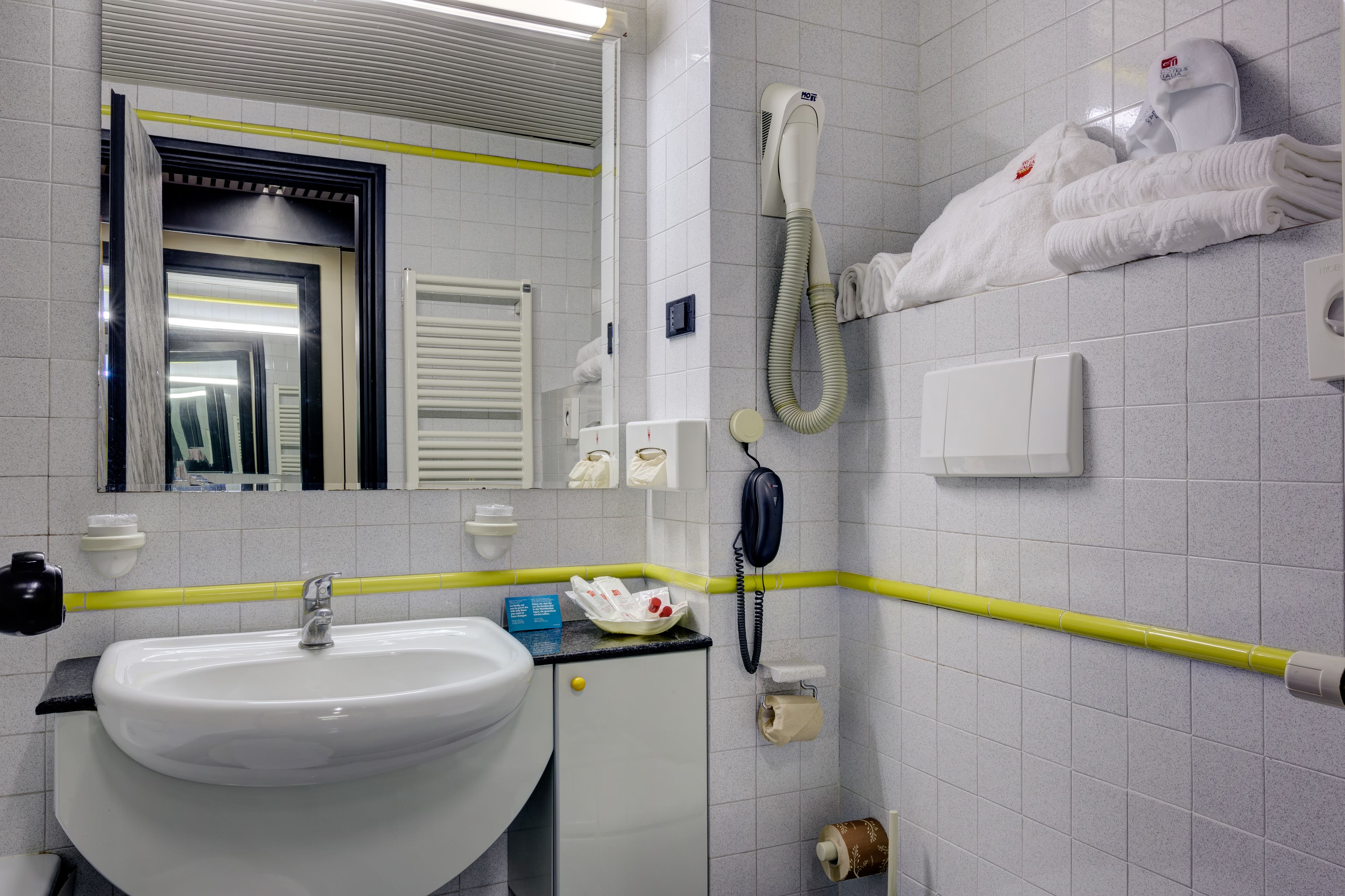 A bathroom with a sink, mirror, towel rack, and a hairdryer.