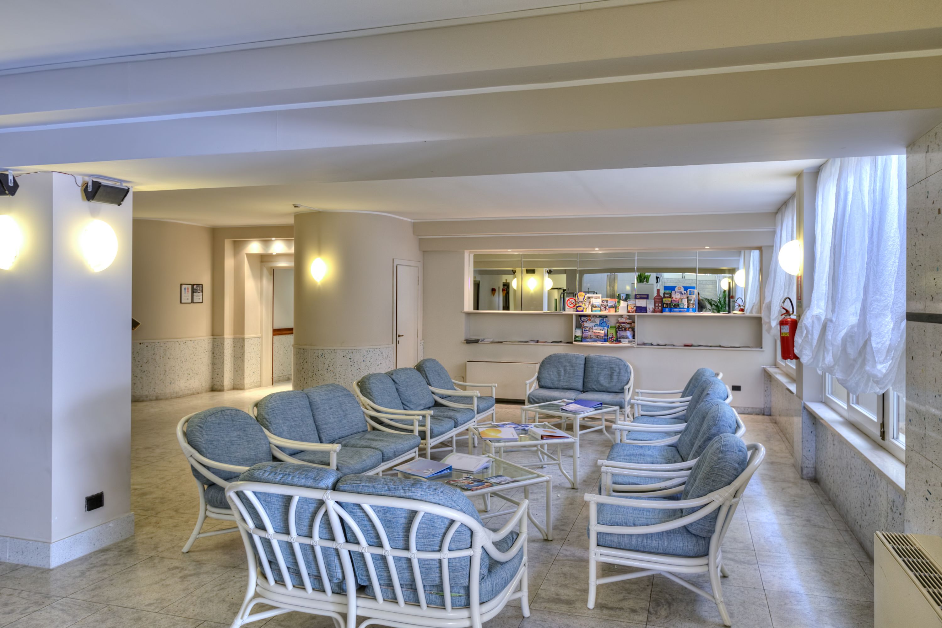 A spacious living area with wicker furniture, a central coffee table, and a kitchen area in the background.