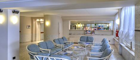 A spacious living area with wicker furniture, a central coffee table, and a kitchen area in the background.