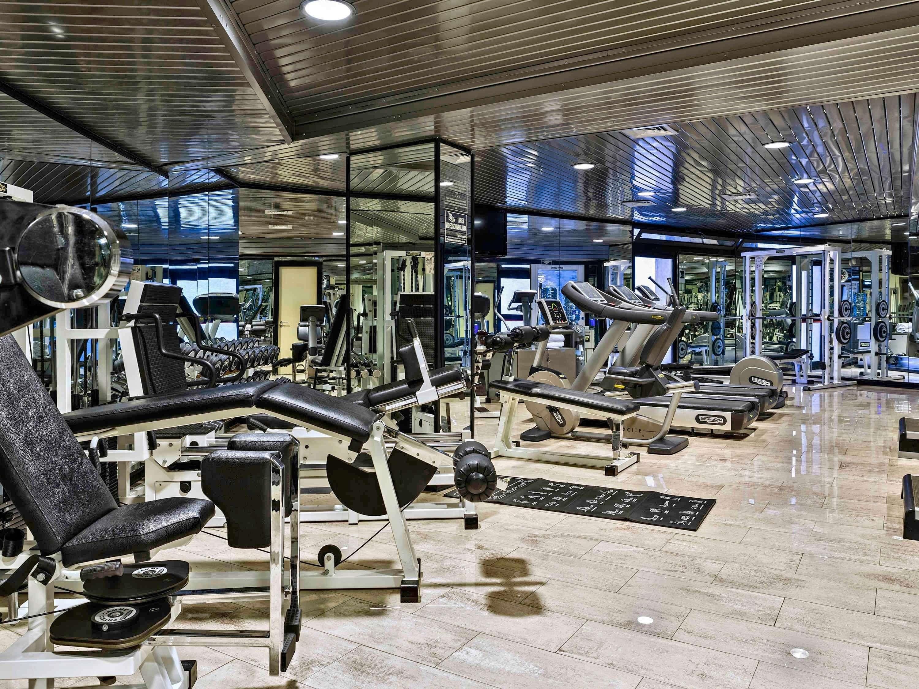 Un gimnasio moderno con diversos equipos de ejercicio, incluyendo cintas de correr, máquinas de pesas y pesas libres.