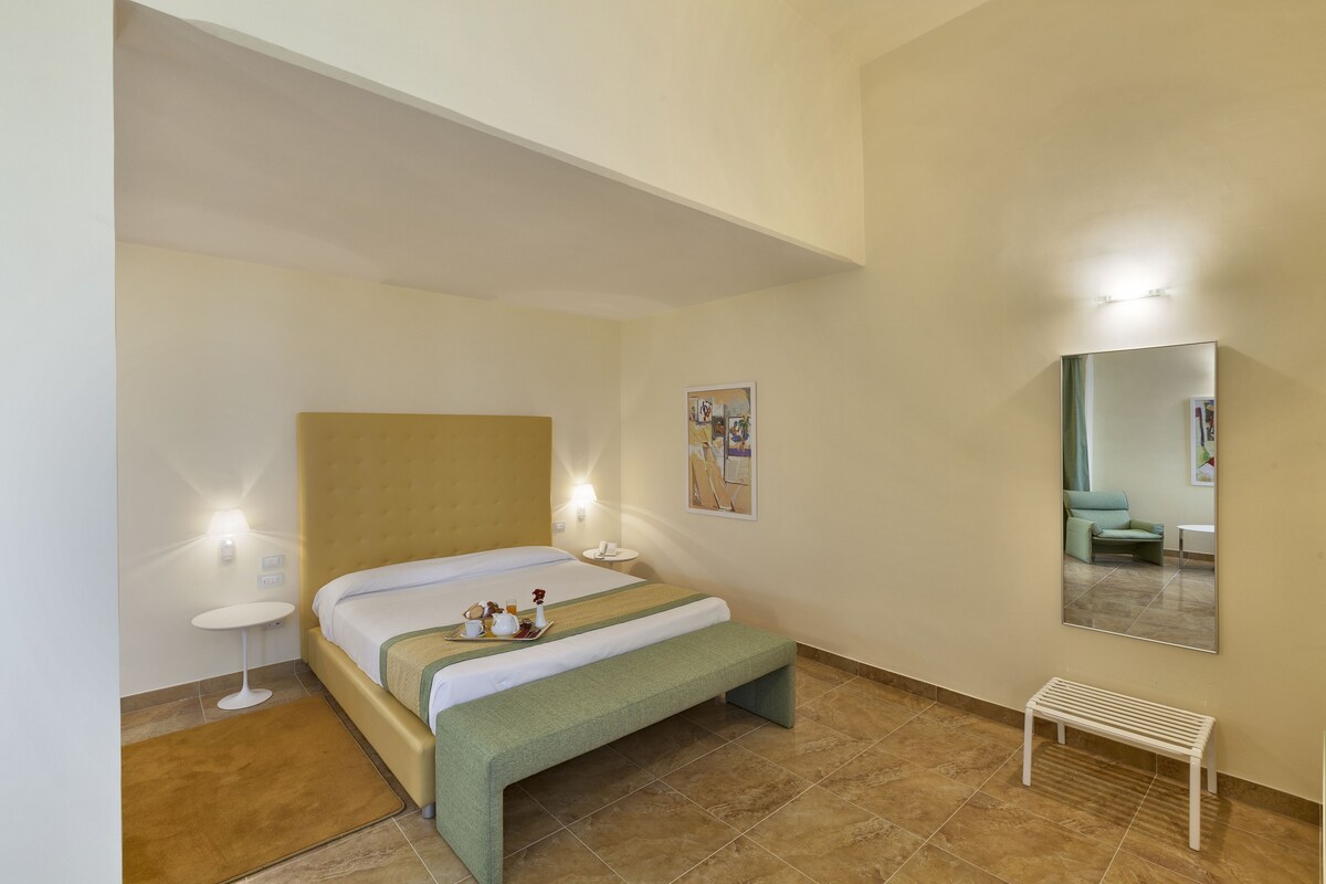 A neatly arranged bedroom with a bed, bedside tables, a bench, and a mirror.