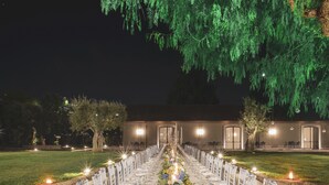 A long table set for a formal event, flanked by white chairs, with a decorative centerpiece and candles. - Mercure Villa Romanazzi Carducci Bari (Bari)