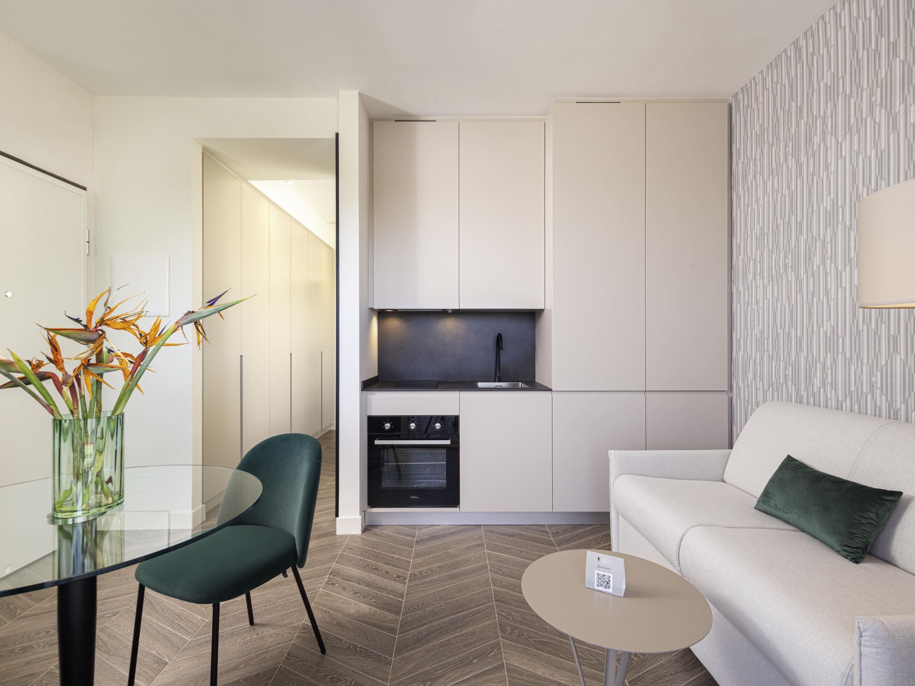 A modern kitchen with white cabinetry, a built-in oven, and a black faucet.