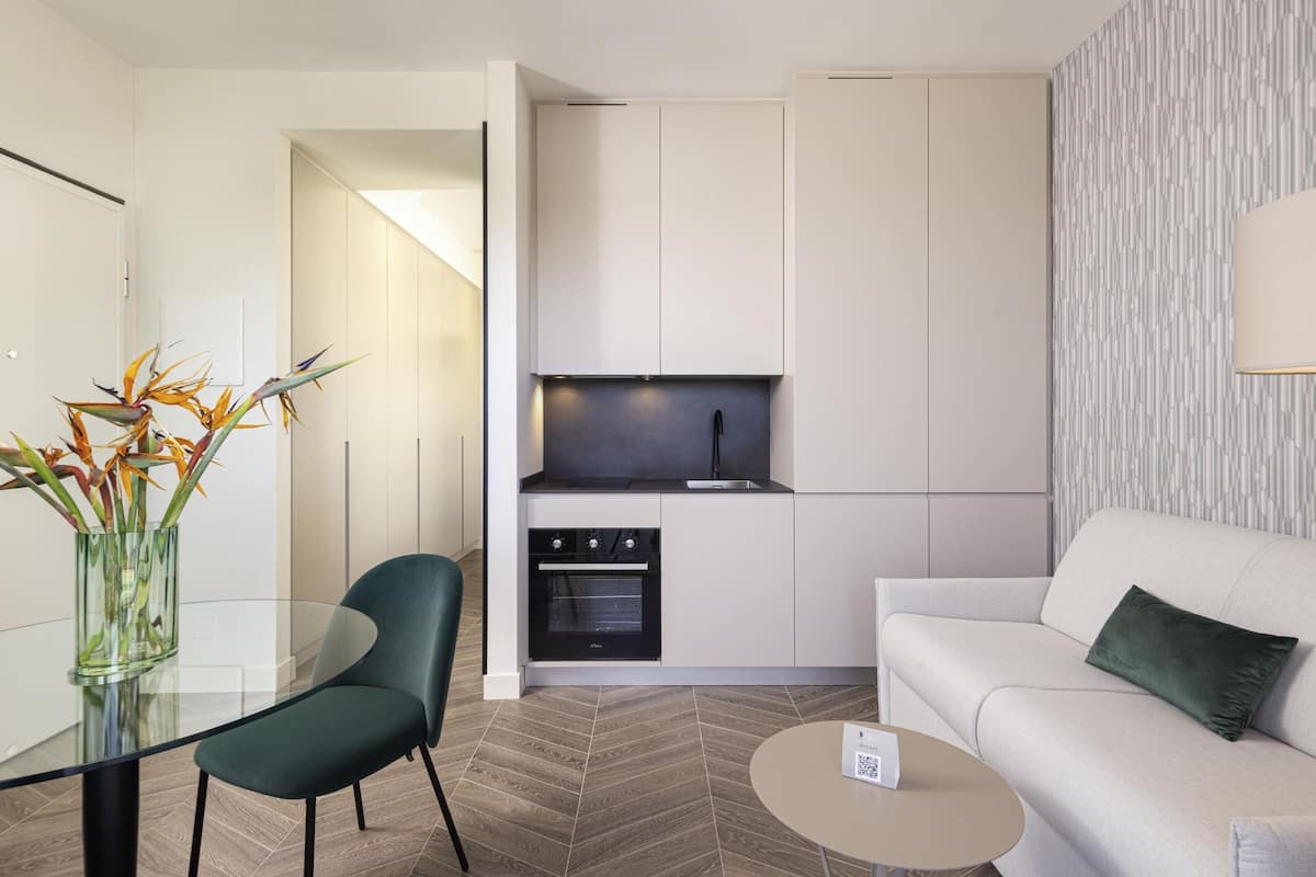 A modern kitchen with white cabinetry, a built-in oven, and a black faucet.