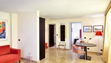 A modern living room with a red sofa, a dining area with a round table and chairs, and a kitchen visible in the background.