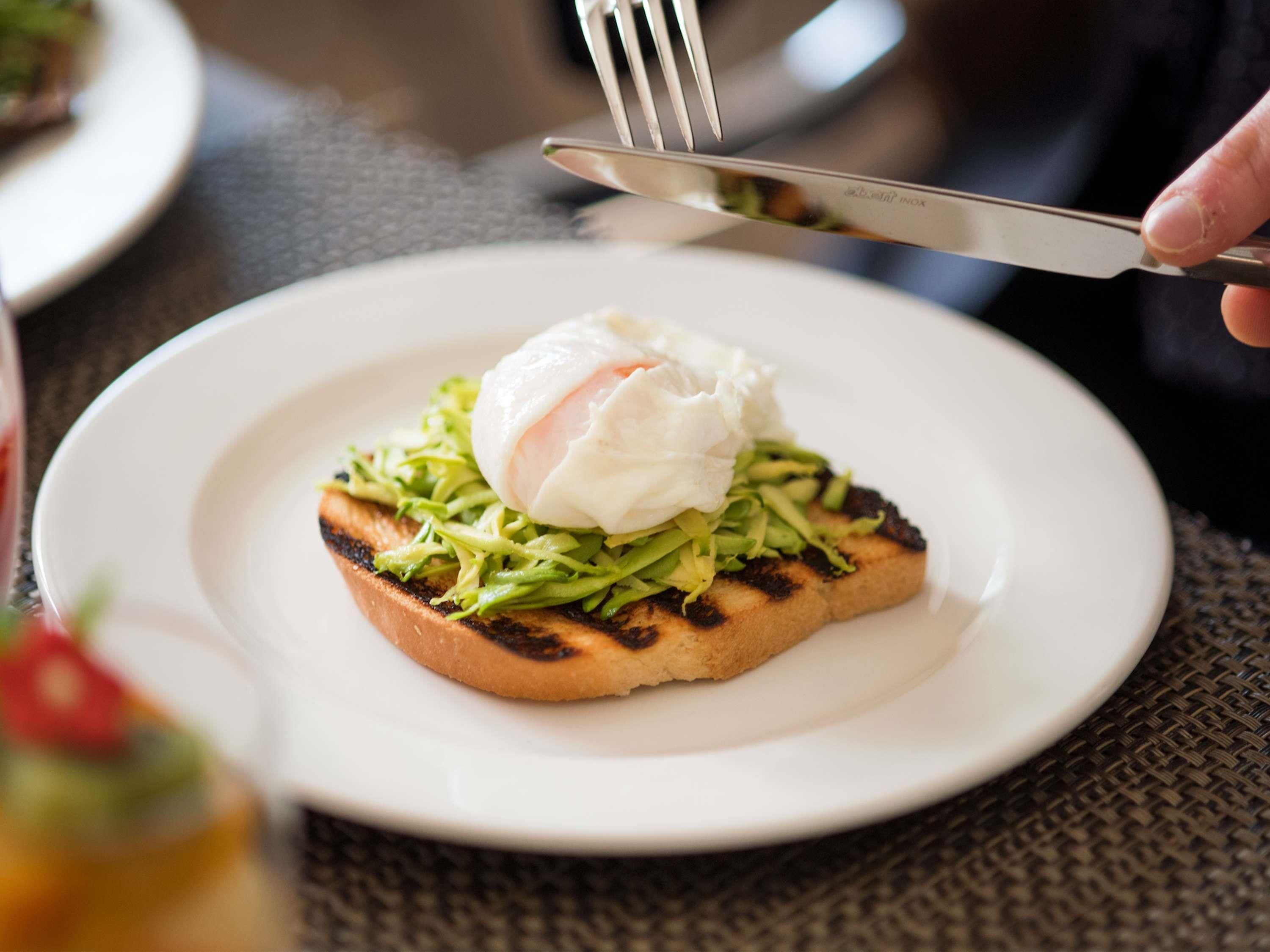 A plate with a grilled item topped with greens and a poached egg.