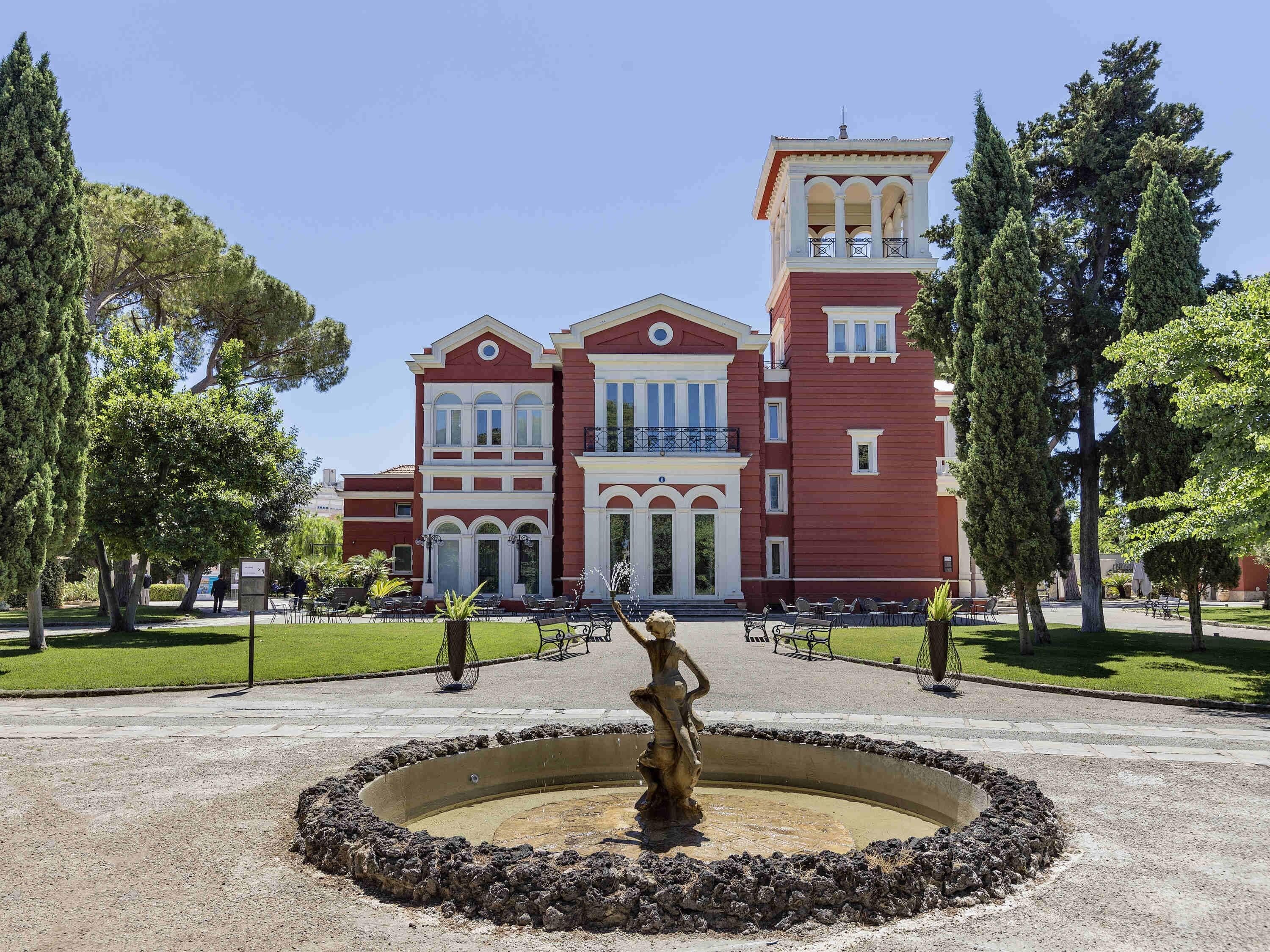 Ein großes, rotes Gebäude mit einem Innenhof, der eine Statue beherbergt.