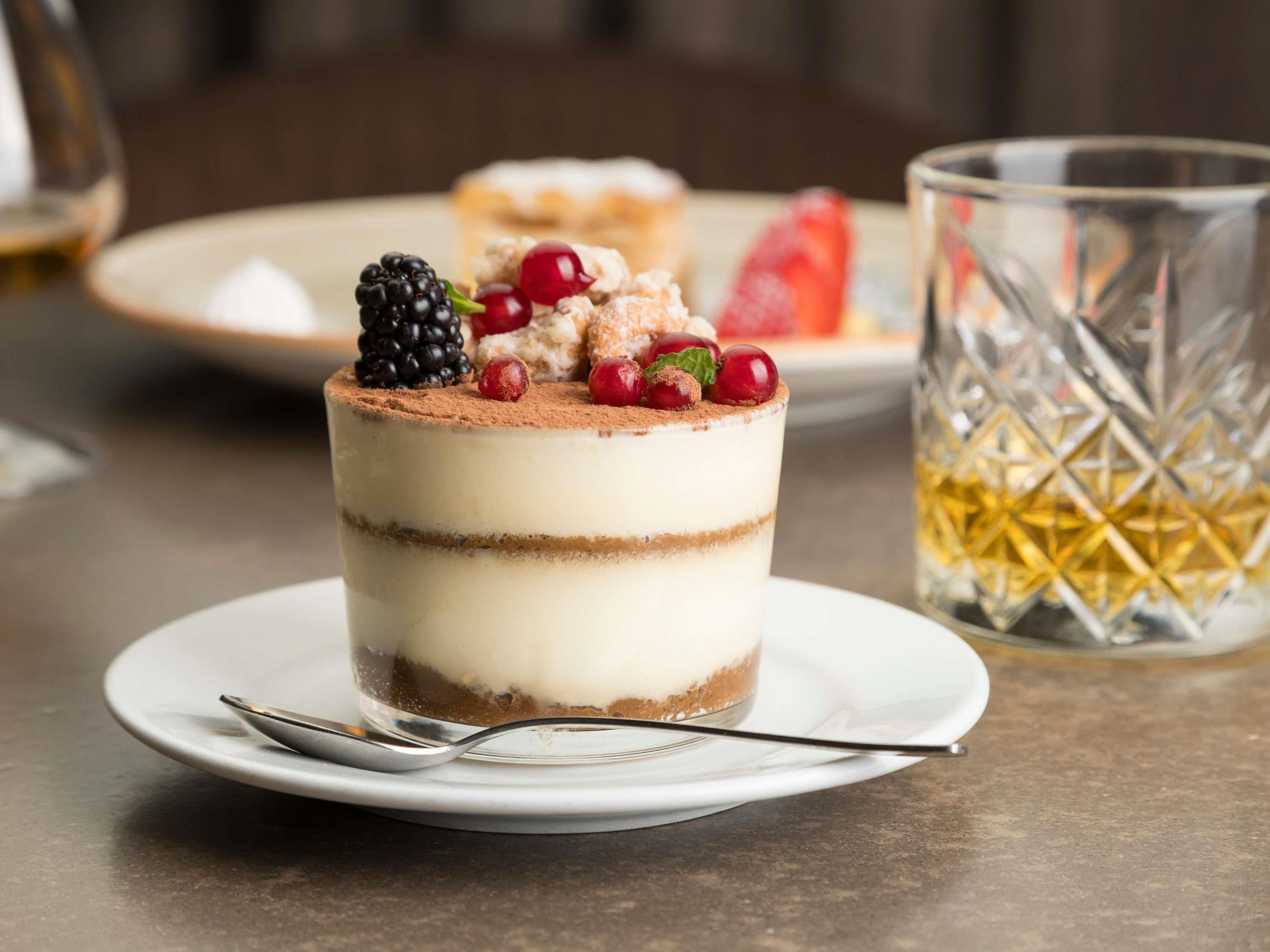 Un dessert composé de plusieurs couches et garni de fruits rouges, présenté dans une assiette.