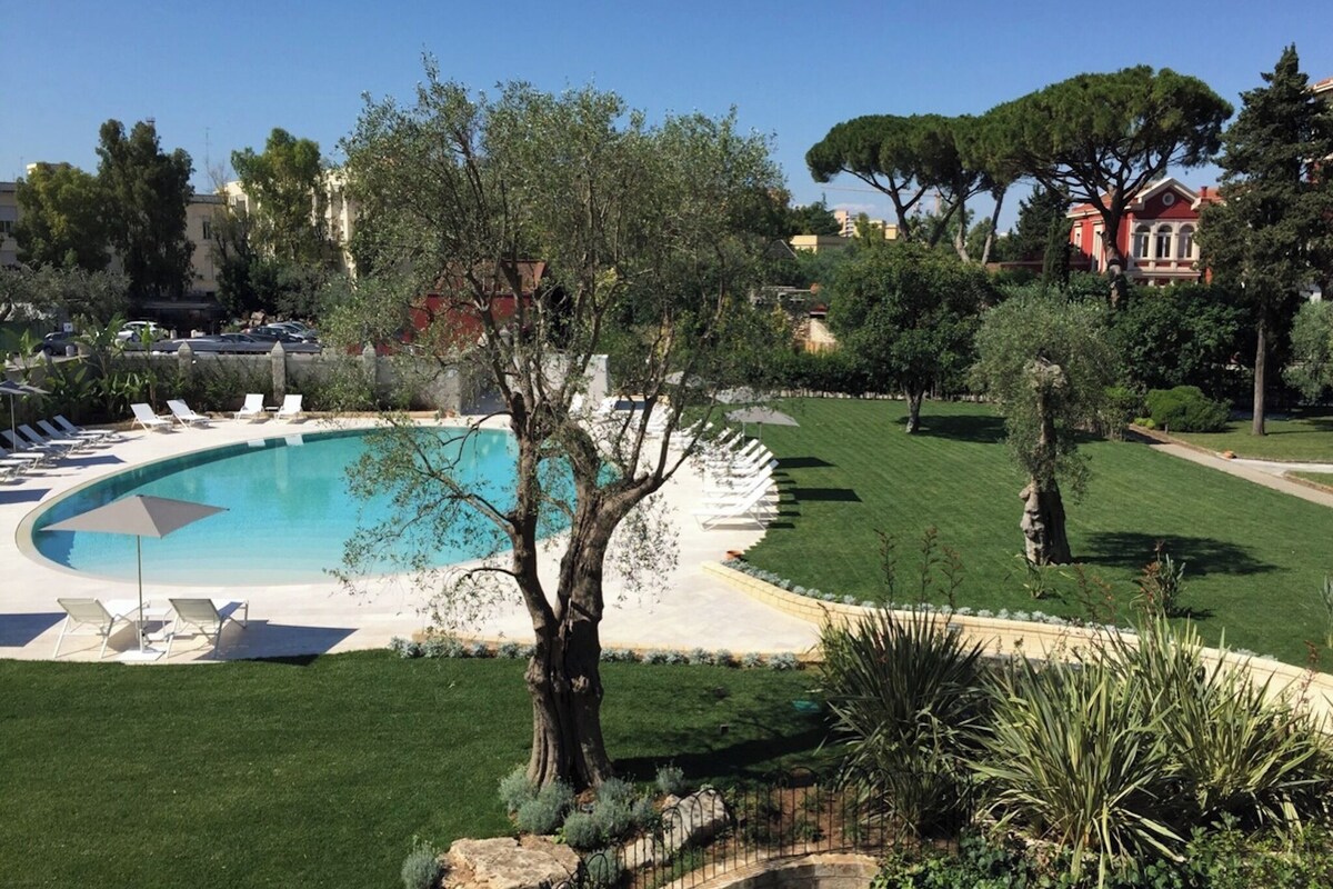 A pool area with lounge chairs, a tree, and a well-maintained lawn.