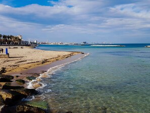A beach with clear water, a sandy shore, and a distant cityscape. - Mercure Villa Romanazzi Carducci Bari (Bari)