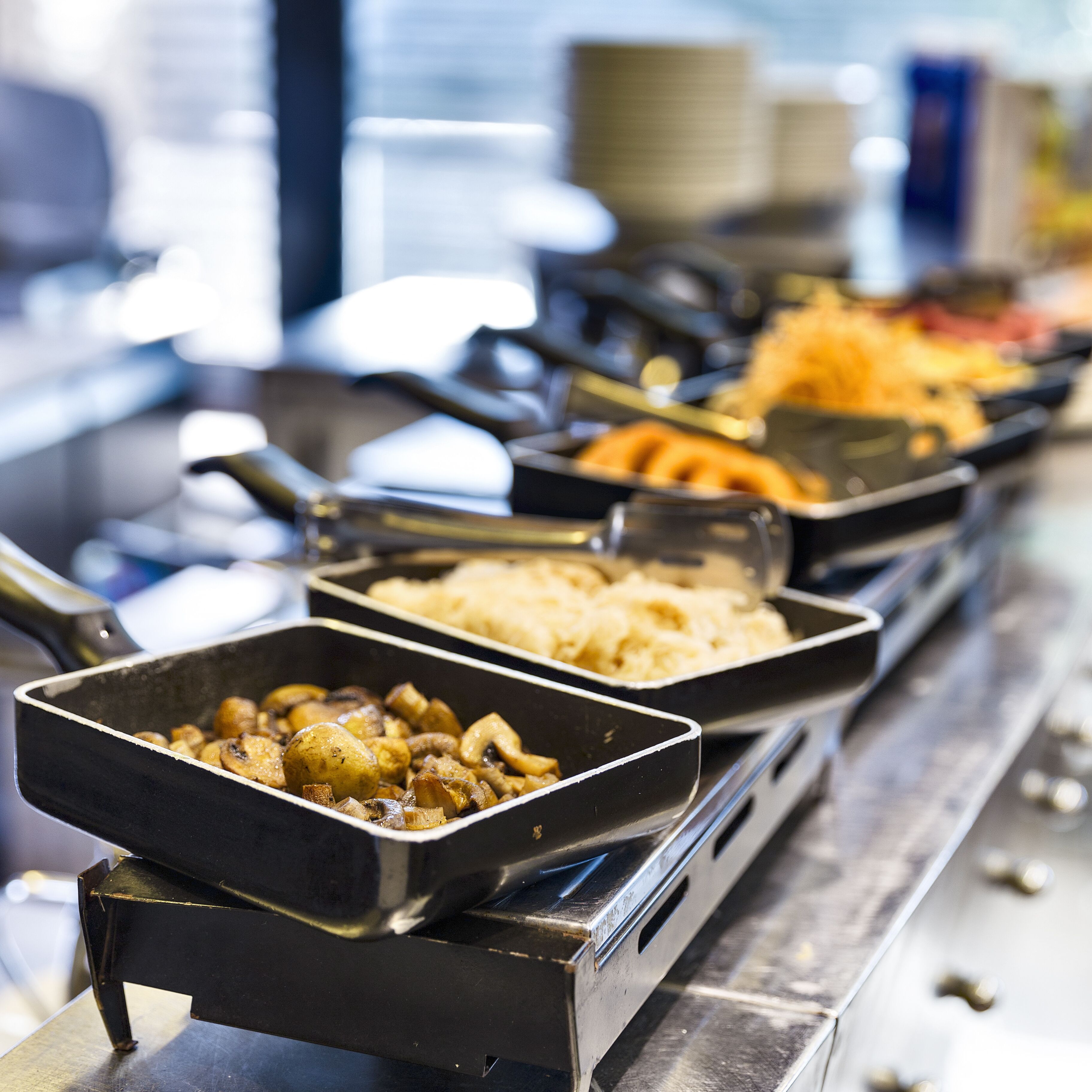 Una barra de buffet con varios platos, incluyendo papas, setas y otras preparaciones.