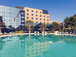 A hotel pool area with clear blue water, sun loungers, and umbrellas. - Mercure Villa Romanazzi Carducci Bari (Bari)