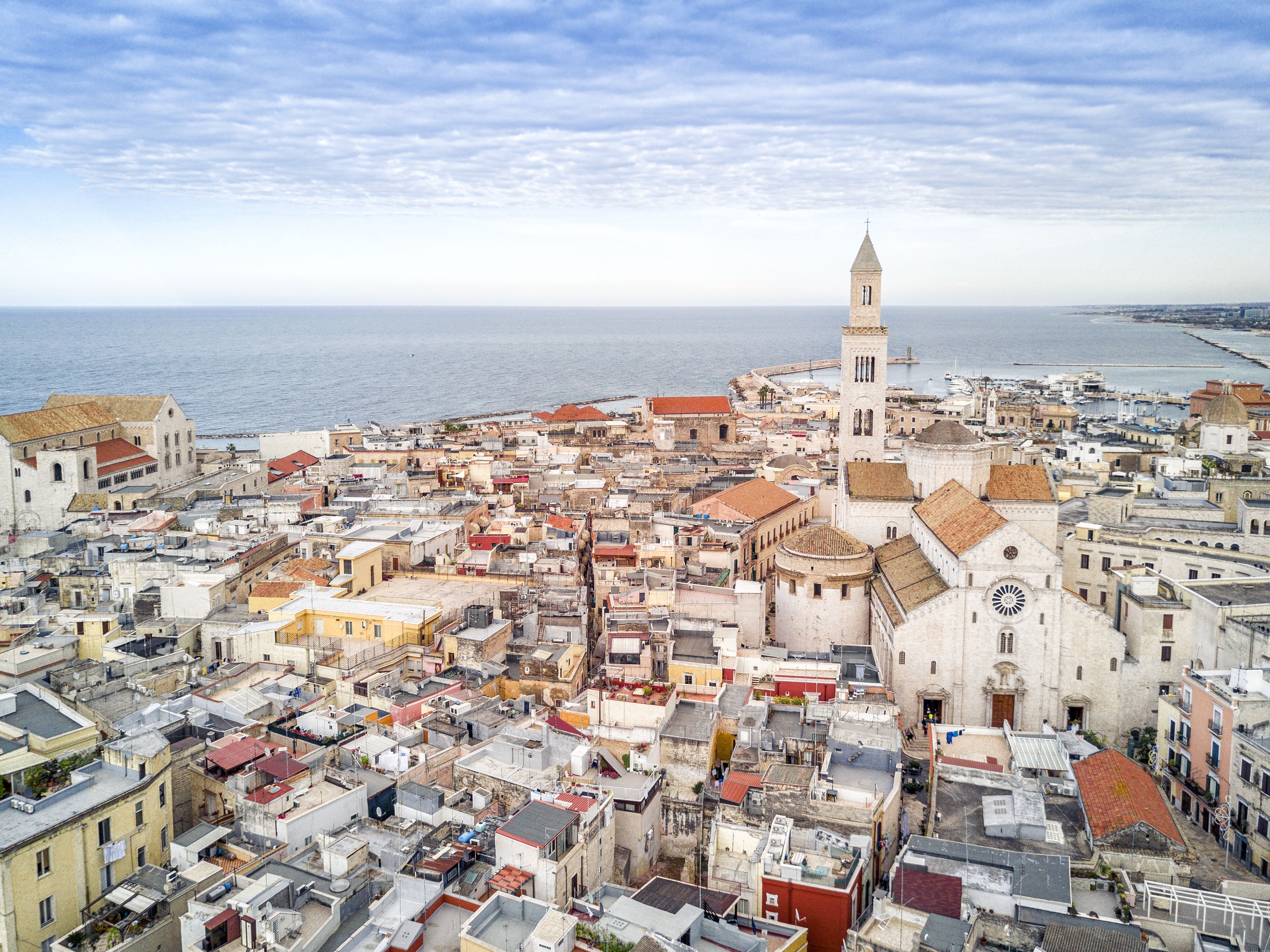 Un paisaje urbano costero con una iglesia destacada y una torre, rodeado de edificios muy juntos.