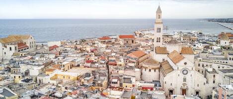 Un paisaje urbano costero con una iglesia destacada y una torre, rodeado de edificios muy juntos.