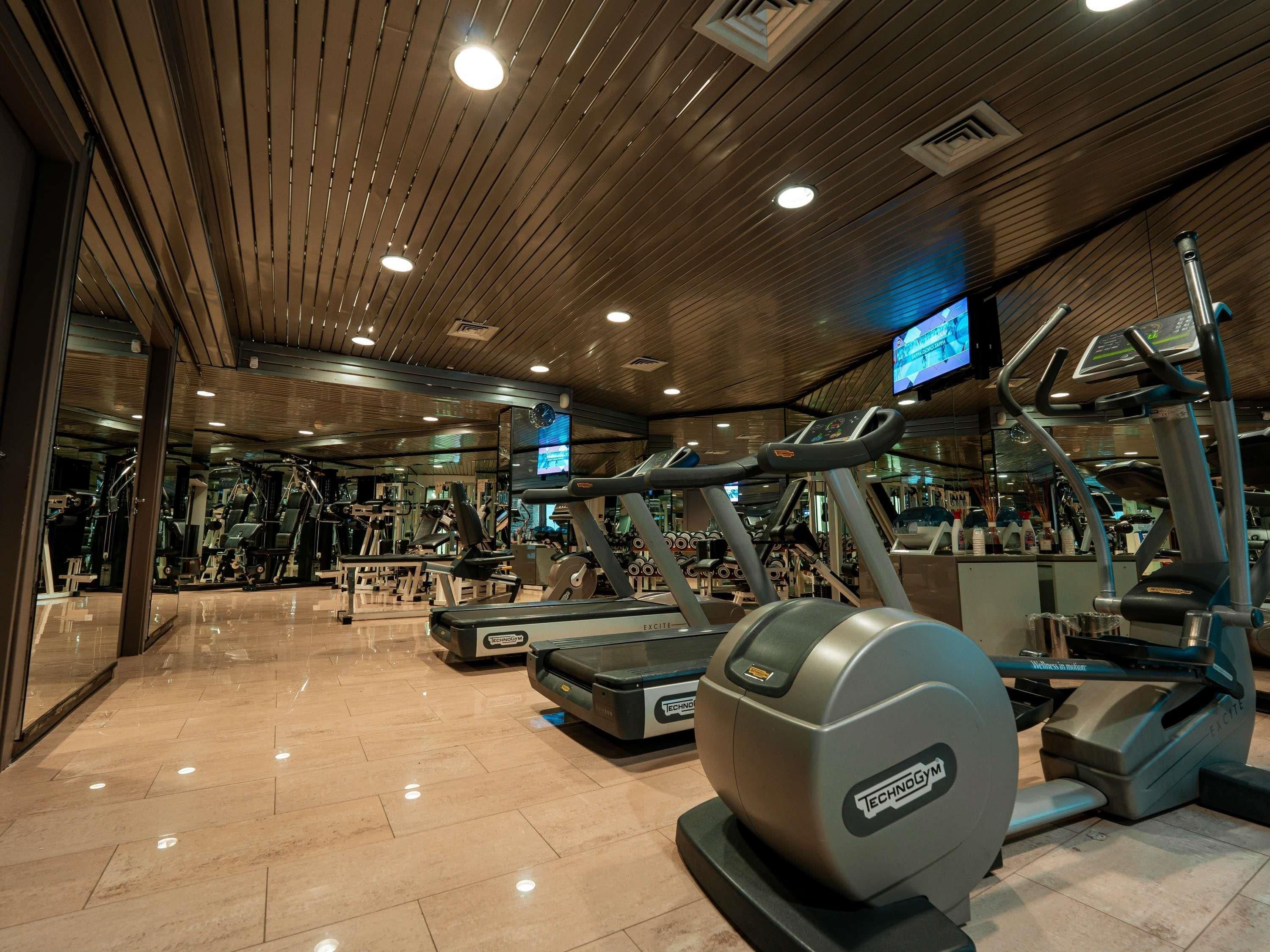 Un gimnasio con cintas de correr, elípticas y máquinas de pesas.