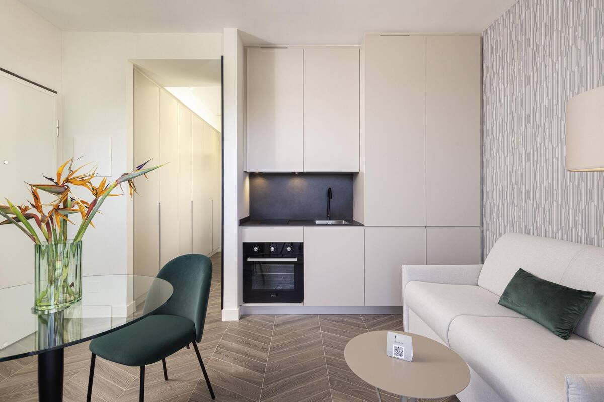 A modern kitchen with white cabinetry, a built-in oven, and a black faucet.