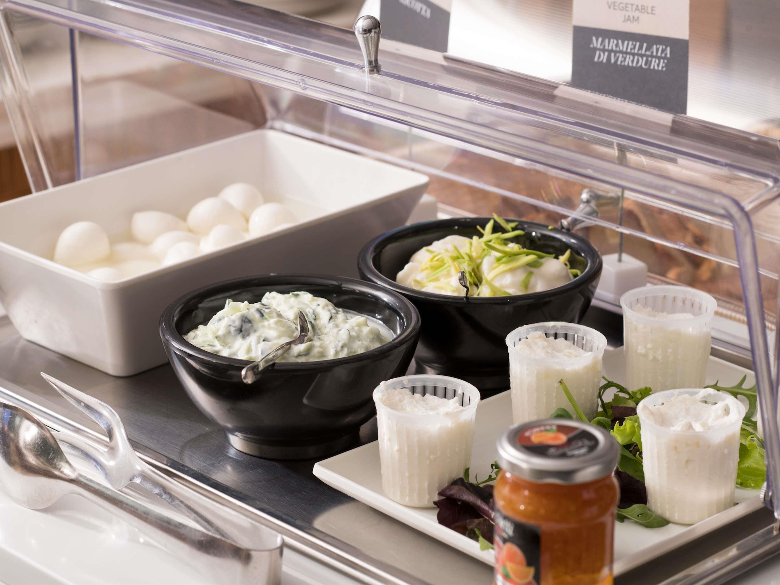 A buffet with various food items including bowls of salad, a container of eggs, and a jar of sauce.
