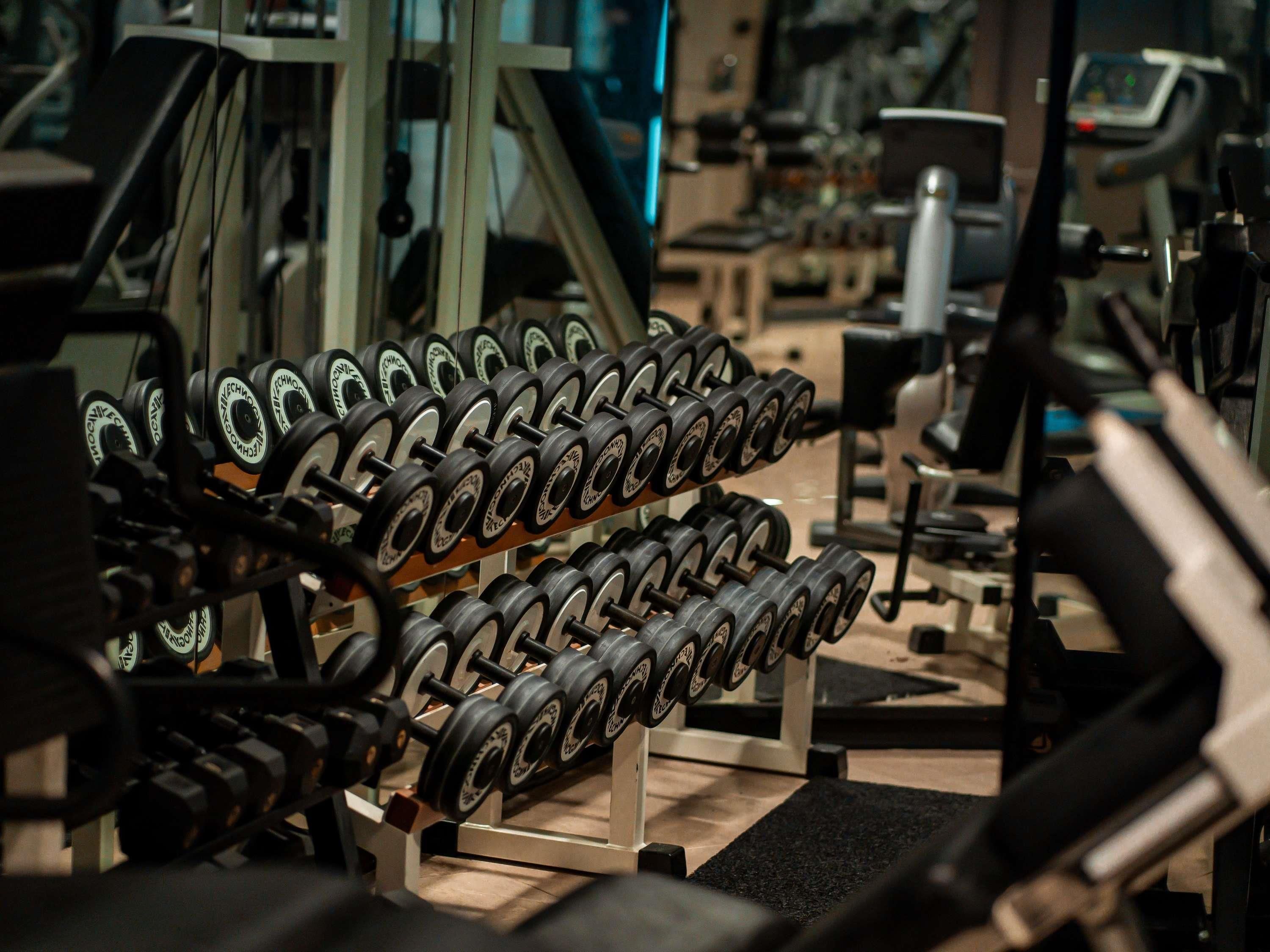 A gym with a rack of dumbbells and exercise equipment.