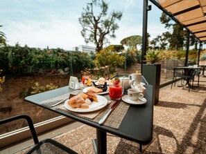 An outdoor dining area with a table set for breakfast, including croissants, a glass of red juice, and a cup of coffee. - Mercure Villa Romanazzi Carducci Bari (Bari)