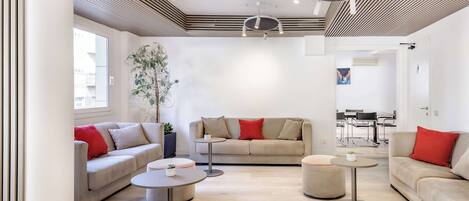 A modern living room with a sofa, two round tables, and a plant.
