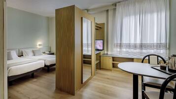 A hotel room with two beds, a desk, a chair, a TV, and a window with curtains.