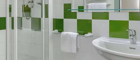 Un baño con ducha de vidrio, un bidé, un lavabo y un espejo.