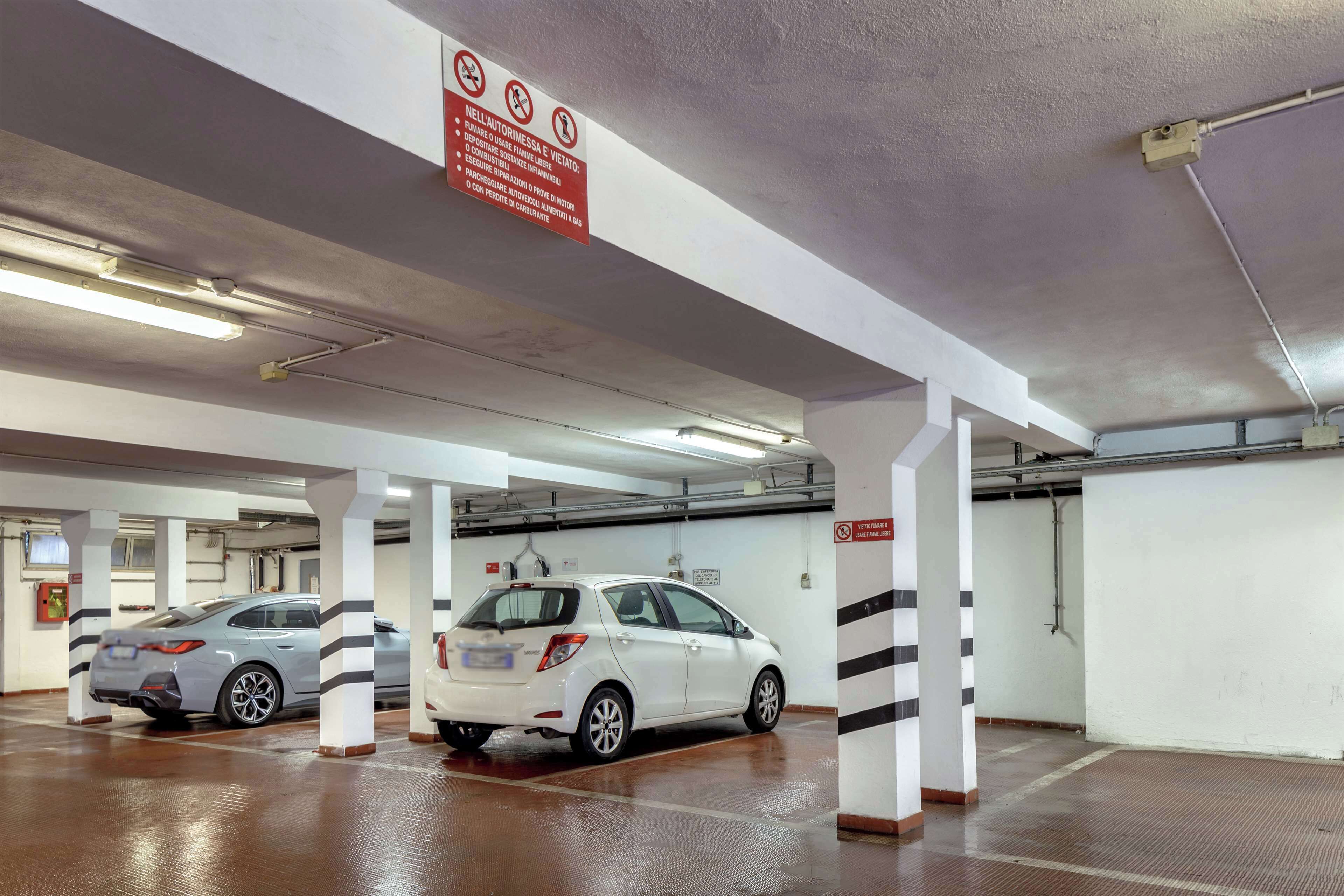 Un garaje para coches con pilares blancos y un coche blanco estacionado al frente.
