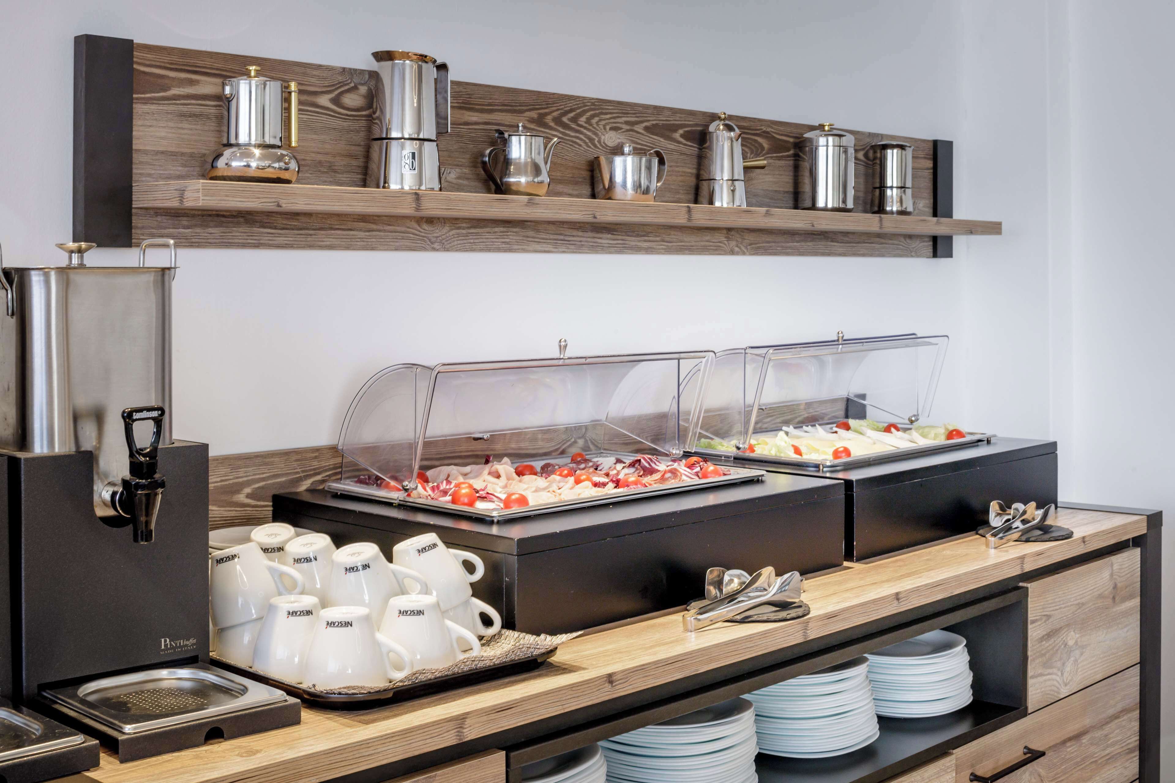 Montaje de bufé con múltiples estaciones de servicio, una máquina de café y una variedad de utensilios y platos.