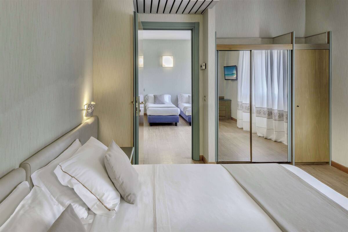 Et hotelværelse med en stor seng, et separat siddeområde og en skydedør til en balkon.