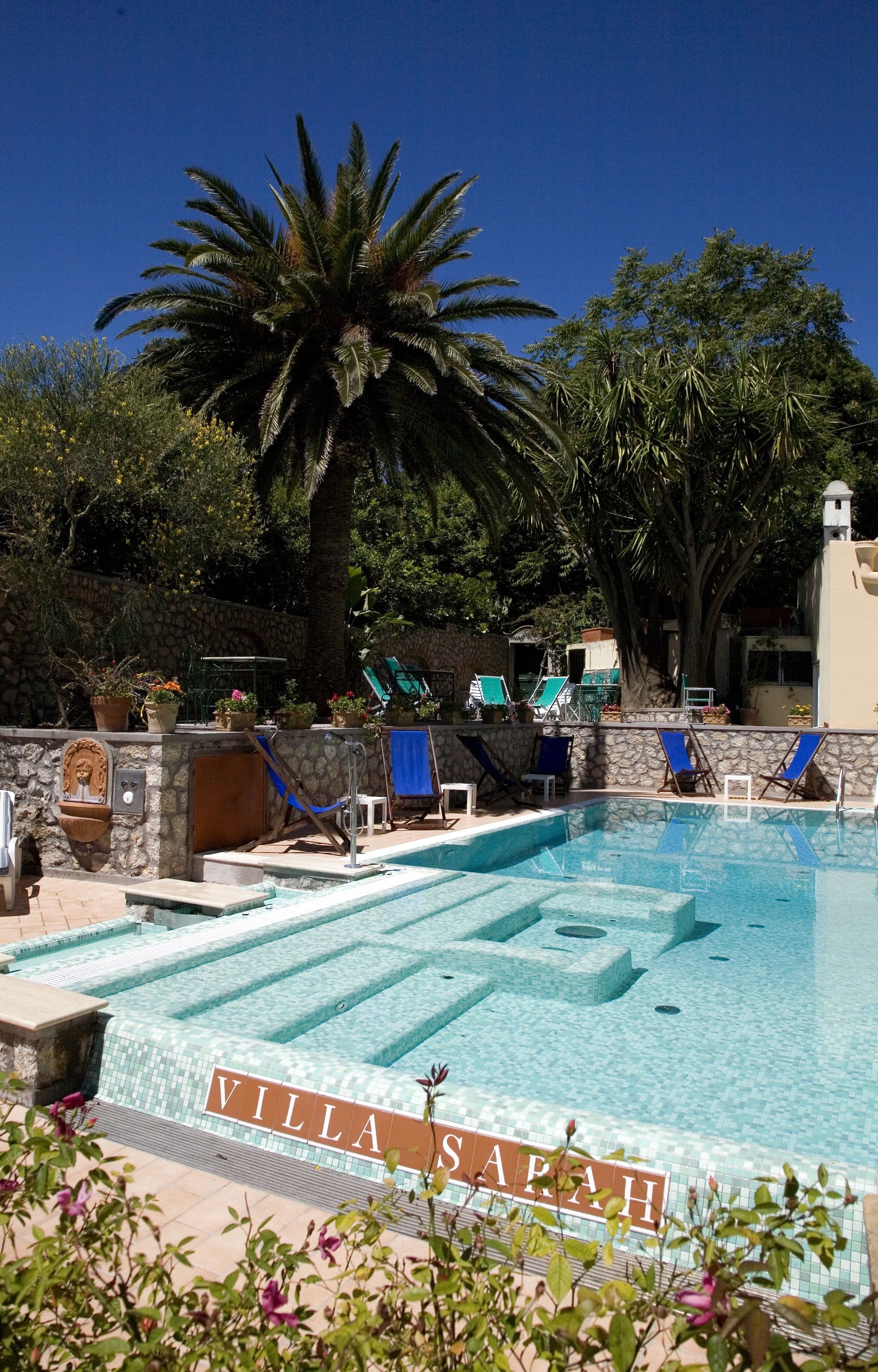 Une piscine avec des chaises longues et un mur en pierre.