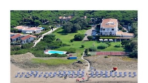 An aerial view of a coastal resort with a beach, swimming pool, and lush greenery. - Hotel Della Baia (Cellole)