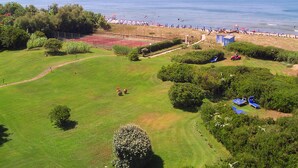 A golf course with a tennis court, a beach, and a small pavilion. - Hotel Della Baia (Cellole)